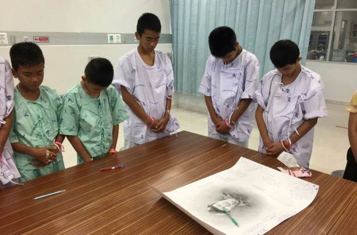 Photo prise le 14 juillet et diffusée le 15 juillet par le ministère de la Santé montre des jeunes footballeurs rescapés d'une grotte en Thaïlande avec un portrait du plongeur mort à l'hôpital de Chiang Rai Prachanukroh