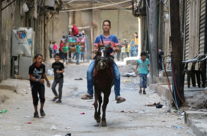 Un garçon syrien monte un cheval dans les rues d'Alep et des enfants jouent lors de l'Aïd au premier jour de la trêve, le 13 esptembre 2016