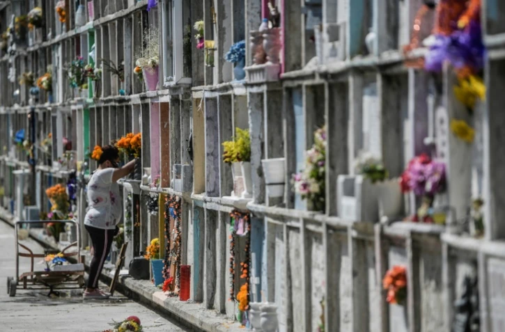 Une femme décore la tombe d'un proche avant le "Jour des morts" au cimetière de Nezahualcoyotl, le 28 octobre 2020 au Mexique