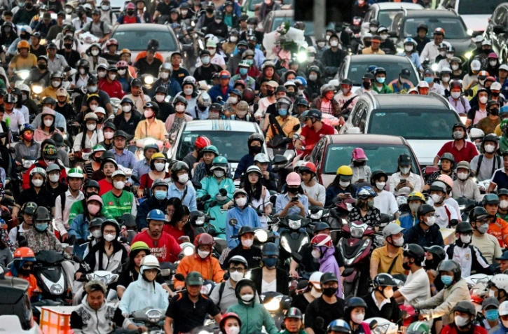 Circulation dense de scooters électriques et d'automobiles dans une rue de Hanoï, le 11 novembre 2024 au Vietnam