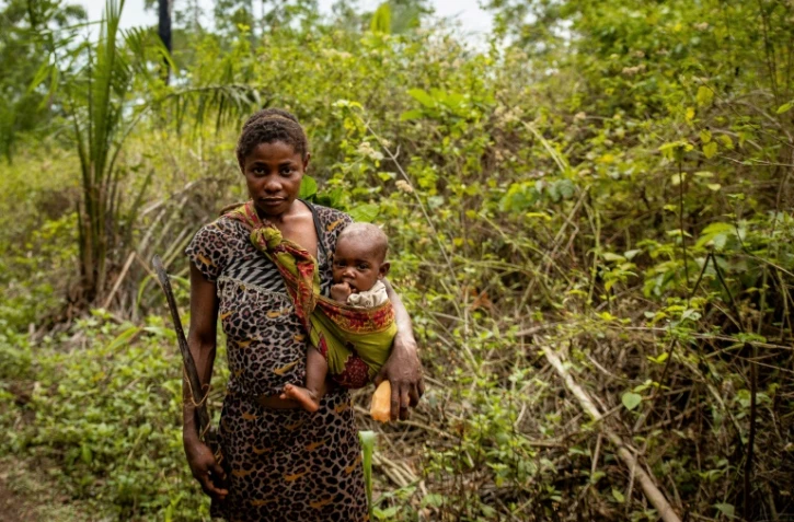 Une jeune pygmée et son enfant à la cueillette de fruits et herbes, à Sakoungou le 11 mars 2022