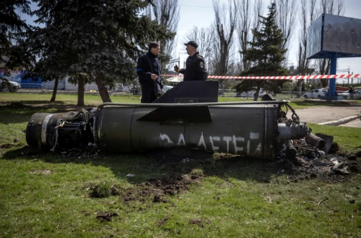 Des policiers ukrainiens devant les débris d'un missile sur lequel est écrit en russe "pour nos enfants" près de la gare de Kramatorsk, cible d'une attaque qui a fait 35 morts, le 8 avril 2022 dans la région du Donbass, dans l'est de l'Ukraine