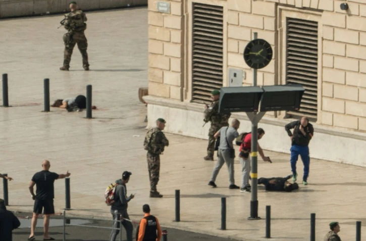 Un policier pointe son arme sur un homme au sol à quelques mètres du corps d'une victime d'une attaque à la gare Saint-Charles de Marseille le 1er octobre 2017