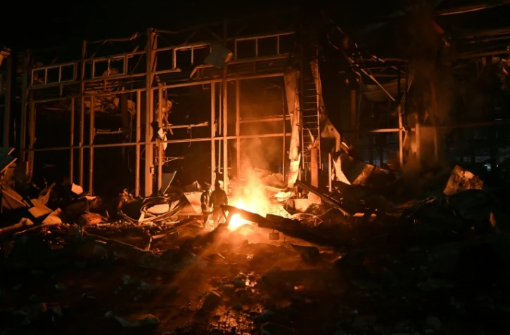 Des pompiers luttent contre un incendie provoqué par un bombardement russe sur un entrepôt de la compagnie des postes Nova Pochta dans un village près de Kharkiv, le 13 janvier 2026 en Ukraine