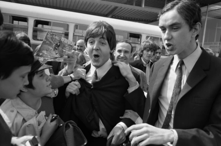 Les membres des Beatles Paul McCartney et George Harrison accueillis par des fans à leur arrivée à l'aéroport d'Orly le 20 juin 1965 avant un concert le soir-même à Paris