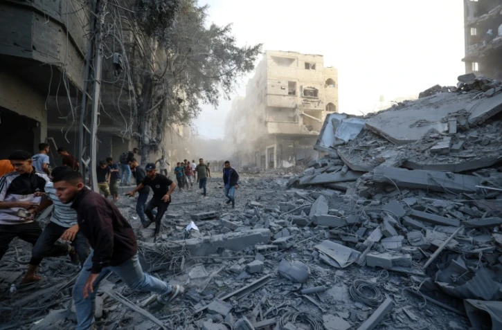 Des personnes courent se mettre à l'abri après une frappe israélienne qui a visé un bâtiment dans le camp de réfugiés palestiniens de Bureij, dans le centre de la bande de Gaza, le 19 octobre 2025