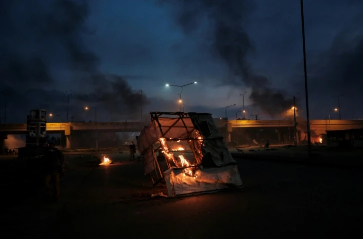 Des débris en feu gisent sur la route après que des partisans de Raila Odinga, candidat à la présidentielle kenyane, ont protesté contre les résultats, à Kisumu, dans l'ouest du Kenya, le 15 août 2022
