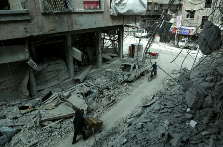 Des Syriens au milieu des destructions dans la ville de Douma, dans la partie rebelle de la Ghouta orientale près de Damas, le 8 mars 2018