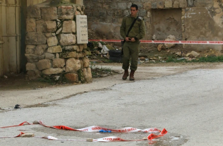 Un militaire israélien surveille le lieu où une jeune Palestinienne a tenté de poignarder un soldat israélien avant d'être abattue, dans la ville d'Hébron, le 13 février 2016
