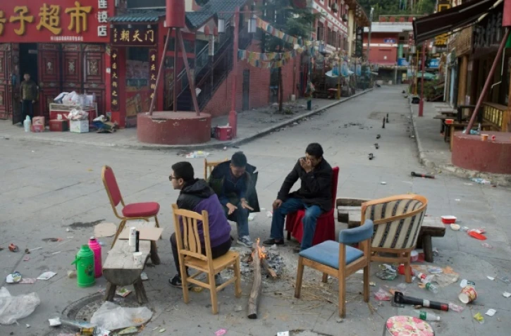 Des habitants qui ont dormi dehors par crainte de répliques tentent se se réchauffer autour d'un feu à Zhangzha dans la province du Sichuan (sud-ouest de la Chine) le 10 août 2017 au surlendemain d'un puissant séisme qui a fait au moins 20 morts