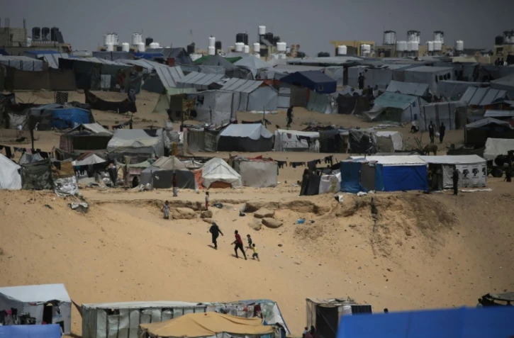 Des Palestiniens marchent dans un camp de personnes déplacées à Rafah, dans le sud de la bande de Gaza, près de la frontière avec l'Egypte, le 28 avril 2024