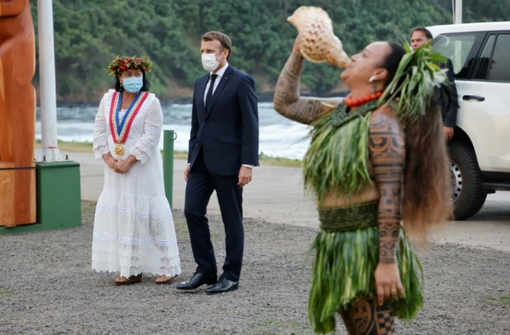 Emmanuel Macron (c) et la maire de Hiva Oa, Joëlle Frebault, assistent à une cérémonie de bienvenue, à Atuona, sur les îles Marquises, le 25 juillet 2021