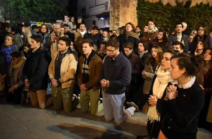 Des fidèles prient devant la cathédrale de Notre-Dame de Paris le 15 avril 2019