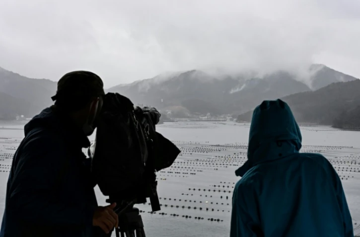 Des personnes observent des volutes de fumée s'échappant d'une montagne, près de la ville d'Ofunato, dans la région japonaise d'Iwate, le 5 mars 2025 