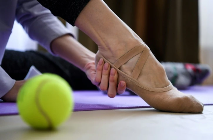 Margarita Chraïner, danseuse du Bolchoï, masse ses pieds avant une séance d'entraînement dans la chambre de son appartement, le 29 avril 2020 à Moscou