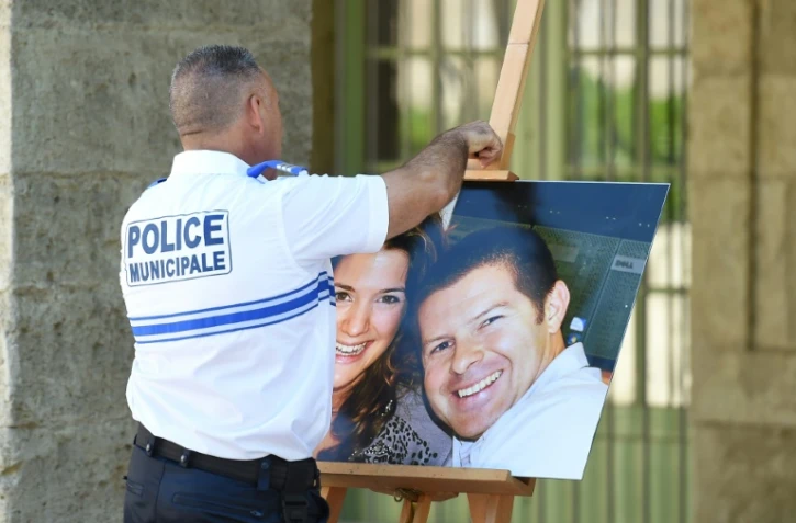 Un officier de police tient le 20 juin 2016 à Pézénas dans l'Hérault une photographie de Jessica Schneider et Jean-Baptiste Salvaing, victimes d'un assassinat jihadiste à Magnanville, le 13 juin 2016