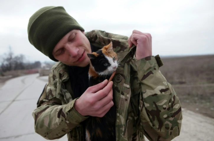 Un soldat ukrainien et son chat à un checkpoint près de Sartana, dans l'est de l'Ukraine, le 29 février 2016