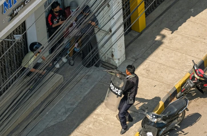 Un policier pointe son arme vers des manifestants à Taunggyi (Birmanie) le 28 février 2021