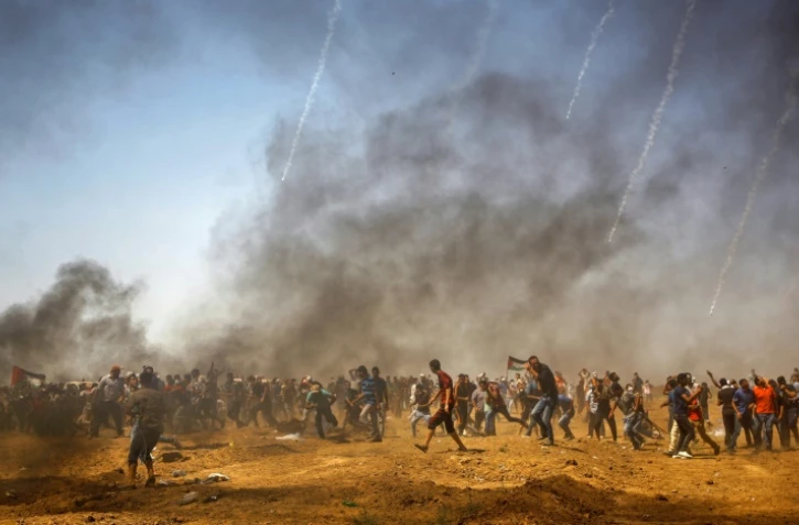 Des manifestants palestiniens se protègent des gaz lacrymogènes israéliens pendant une manifestation à Jabalia, au centre de la bande de Gaza, le 8 juin 2018