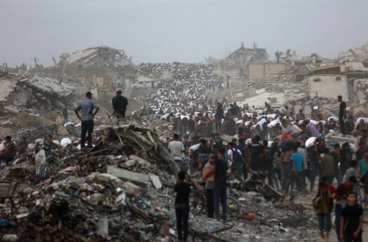 Des Palestiniens, au milieu des décombres sur le chemin côtier de Beit Lahia, dans la bande de Gaza, transportent l'aide alimentaire qu'ils ont pu se procurer le 29 juillet 2025