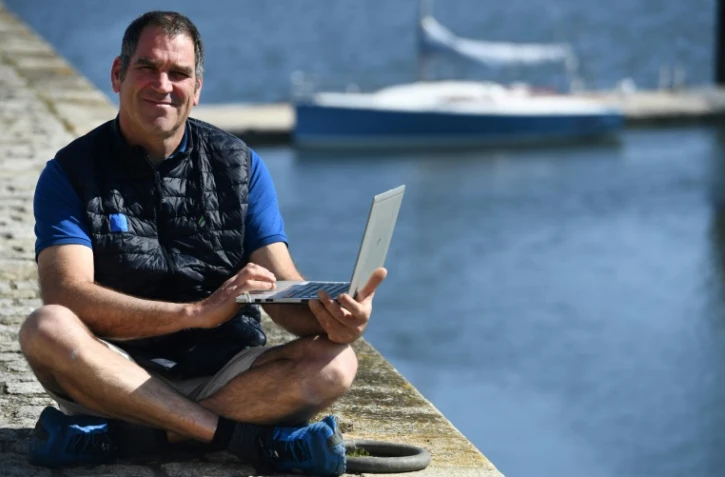 Le skipper français Gildas Morvan pose avec son ordinateur utilisé pour participer à la course virtuelle, le 6 mai 2020 à Landéda (Finistère).