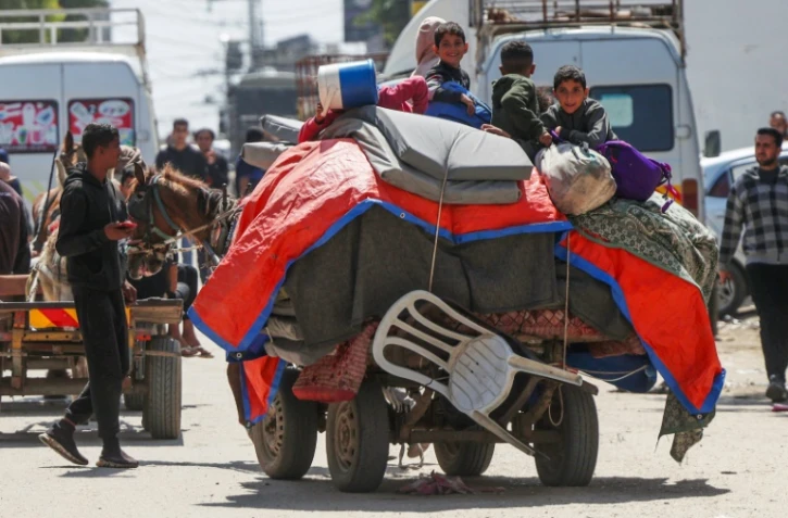 Des enfants palestiniens assis sur leurs affaires, rassemblées dans une charrette à cheval, à Nousseirat (centre de la bande de Gaza), le 12 avril 2024