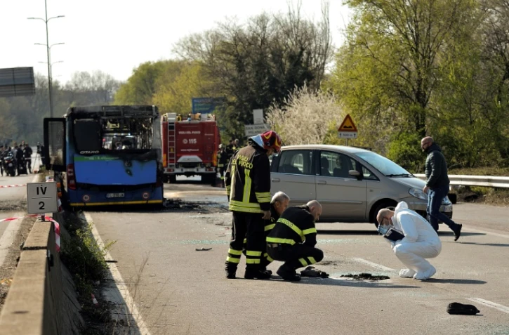 La police scientifique italienne et des pompiers près de la carcasse d'un bus de transport scolaire incendié par son chauffeur le 20 mars 2019 à San Donato Milanese, près de Milan