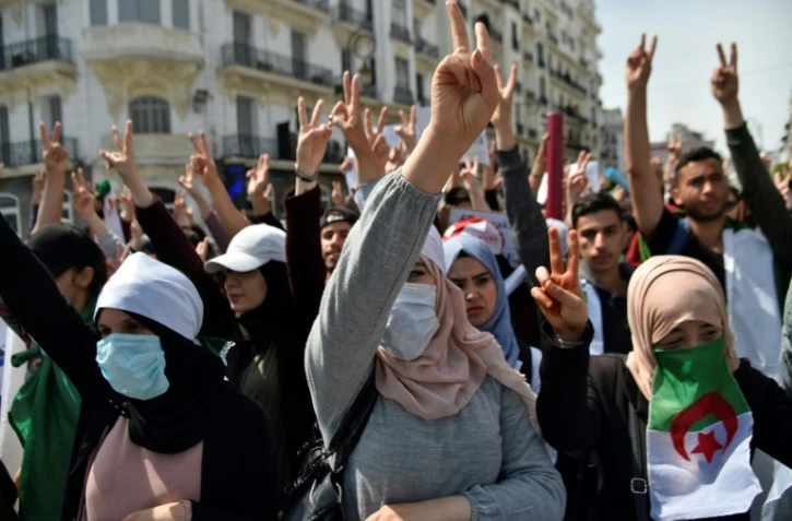 Des manifestants algériens font le V de la victoire lors d'une manifestation anti-gouvernementale à Alger le 23 avril 2019