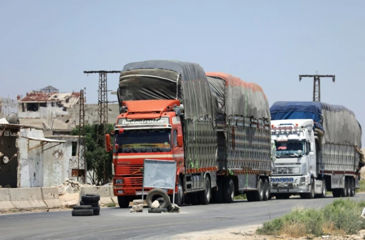 Des camions chargés de marchandises attendent d'être contrôlés au point de passage de Morek, entre les zones du régime à Hama et celles contrôlées par les jihadistes et rebelles dans la province d'Idleb, le 8 juillet 2018