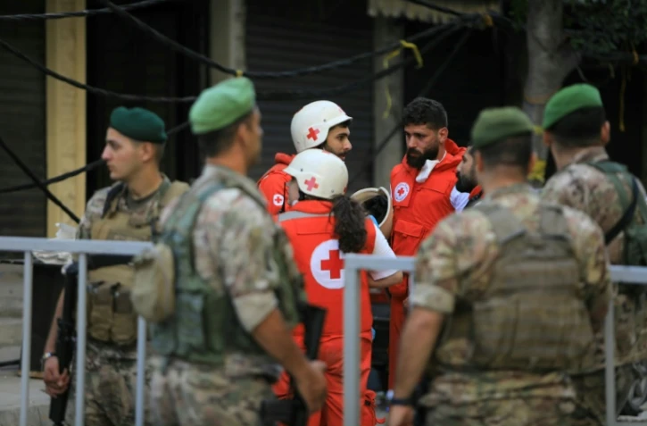 Secouristes et soldats libanais rassemblés sur les lieux de la frappe israélienne de la veille sur la banlieue sud de Beyrouth, le 21 septembre 2024