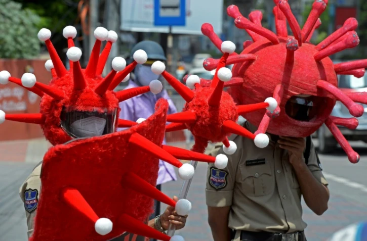 Des policiers portant des déguisements sur le thème du coronavirus, pour inciter les habitants à respecter les restrictions sanitaires, sont postés à un carrefour de Hyderabad (Inde), le 27 mai 2021