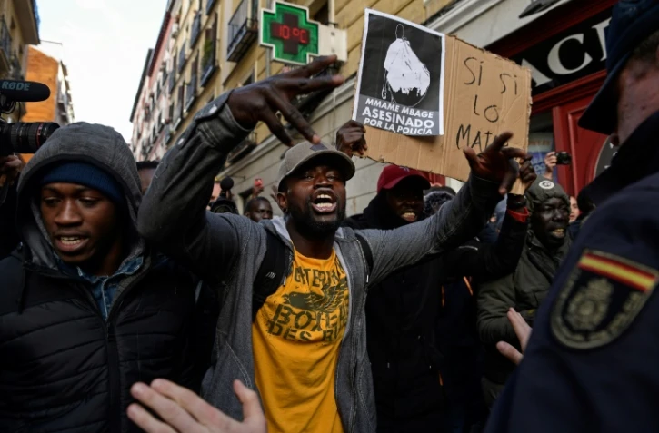 Des manifestants face à des policiers dans un quartier de Madrid, le 16 mars 2018, au cours d'un rassemblement à la mémoire d'un vendeur des rues sénégalais 