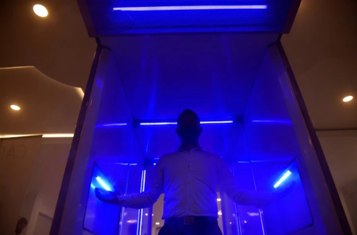 Un homme montre le fonctionnement d'une cabine automatique de désinfection, qui doit aider à lutter contre le coronavirus, à Bogota le 10 août 2020