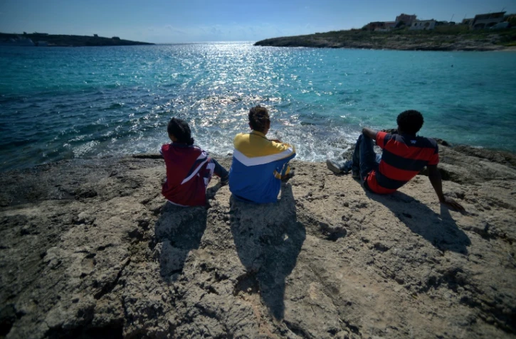 De jeunes migrants regardent la mer depuis l'île de Lampedusa