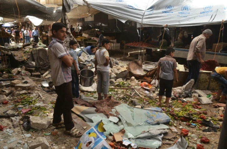 Des Syriens au milieu des décombres après des tirs attribués à des rebelles le 4 juin 2016 à al-Midan dans la banlieue d'Alep