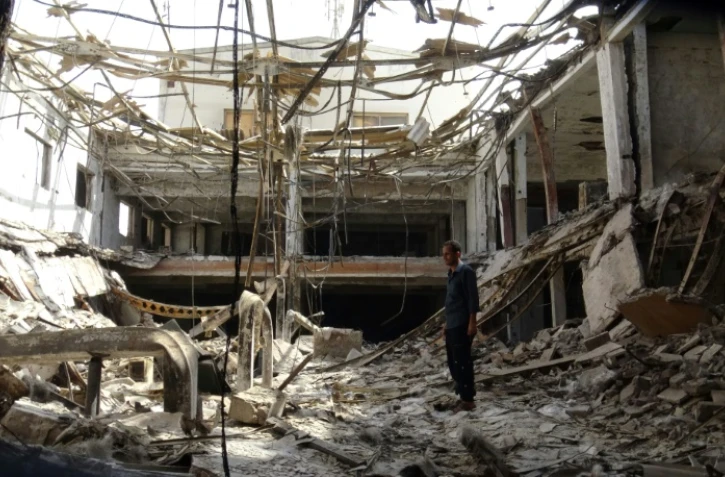 Un homme debout au milieu des décombres d'une usine partiellement détruite par des raids aériens dans la ville de Hodeida au Yémen, le 17 décembre 2018