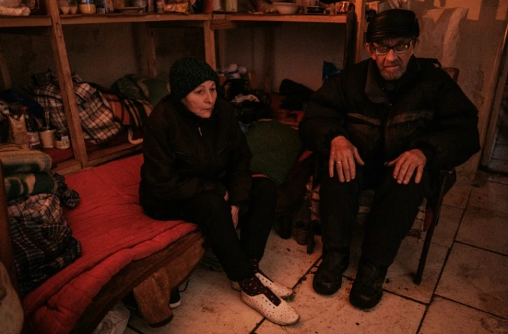 Nadia (g), 68 ans, et son mari Oleksandr, 69 ans, vivent dans un bunker à la lumière d'une bougie dans le Palais de la culture de Roubijné en Ukraine, le 23 avril 2022