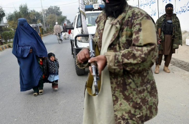 Un femme passe à cause d'un combattant taliban à Jalalabad, Afghanistan, le 12 décembre 2021