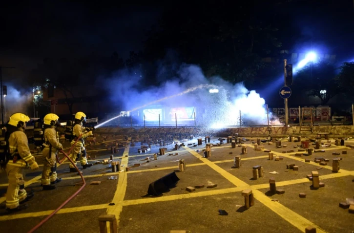 Des pompiers interviennent pour éteindre le feu sur des barricades bloquant une route près de l'université polytechnique de Hong Kong