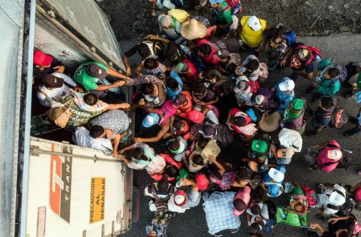 Des migrants honduriens montent à bord d'un camion, près de Pijijiapan, dans le sud du Mexique le 26 octobre 2018