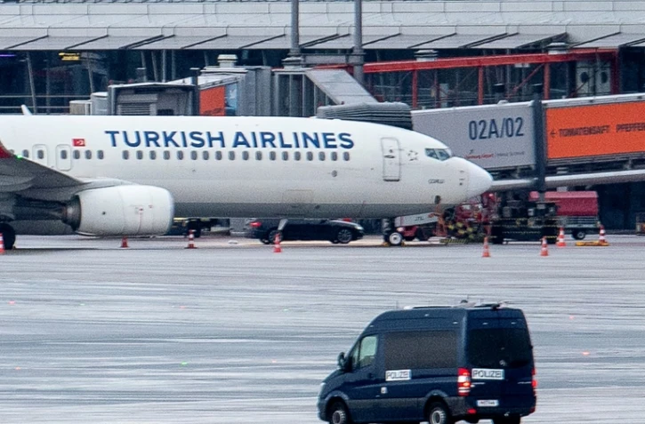 Une camionnette de police observe la voiture d'un preneur d'otages garée sous un avion de la compagnie aérienne turque sur le tarmac de l'aéroport de Hambourg, dans le nord de l'Allemagne, le 5 novembre 2023