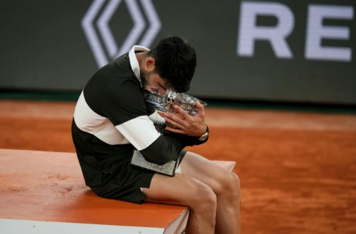 L'Espagnol Carlos Alcaraz enlace le trophée de Roland-Garros après sa victoire en finale sur l'Italien Jannik Sinner, le 8 juin 2025 à Paris