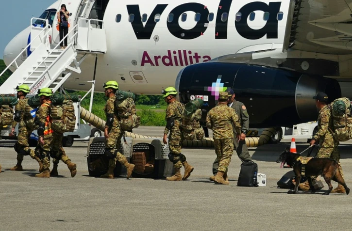 Des militaires salvadoriens accompagnés de chiens renifleurs se préparent à embarquer à bord d’un avion à destination du Venezuela, sur la base aérienne de Comalapa à San Luis Talpa, au Salvador, le 25 juin 2026