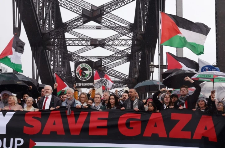 Des manifestants, dont le fondateur de WikiLeaks, Julian Assange (3e en partant de la gauche, l'homme portant une cravate rouge), défilent sur le pont Harbour Bridge à Sydney lors d’un rassemblement pro-palestinien le 3 août 2025.