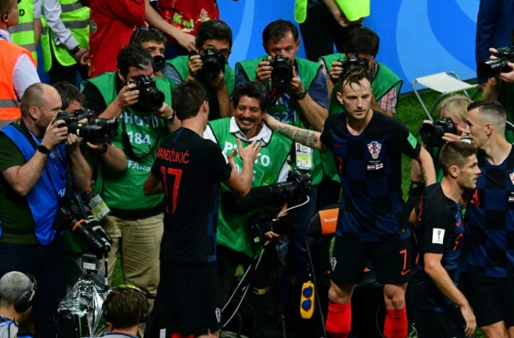 L'attaquant croate Mario Mandzukic (g) serre la main du photographe de l'AFP Yuri Cortez (c) qui a été pris sous une mêlée de joueurs croates qui fêtaient un but en demi-finale du Mondial contre l'Angleterre, le 11 juillet 2018 à Moscou 