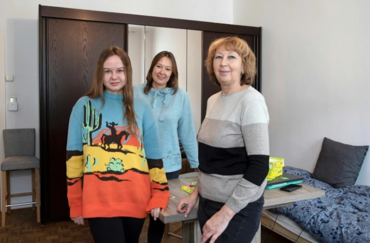 Les Ukrainiennes Maryna Troshchenko (c), sa mère Iryna Simonova (d) et sa fille Katya Troshchenko dans leur appartement à Vienne, le 8 février 2024 en Autriche