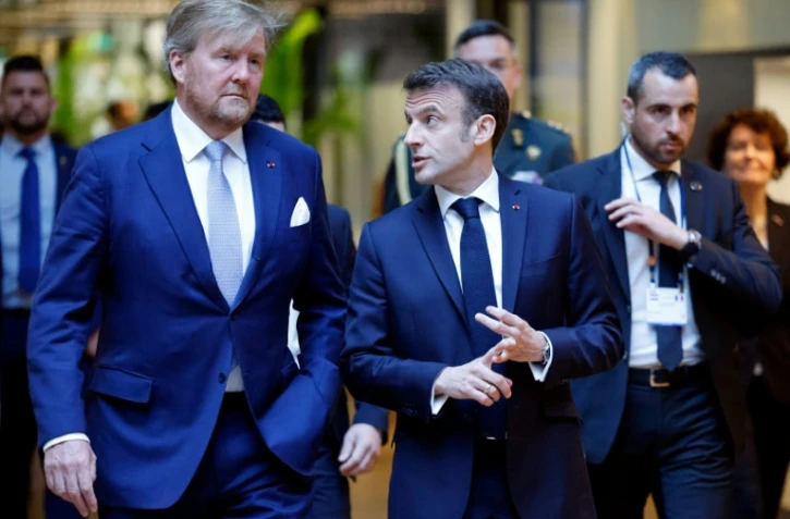 Le président français Emmanuel Macron (c) et le roi des Pays-Bas Willem-Alexander (g) visitent un laboratoire de physique quantique de l'université d'Amsterdam, le 12 avril 2023