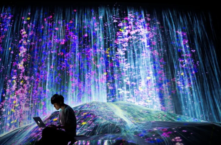 Un membre du collectif japonais teamLab près d'une cascade de lumière au Mori Building Digital Art Museum, le 1er mai 2018 à Tokyo