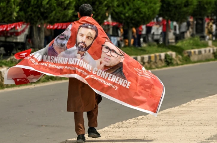 Un partisan de la Conférence Nationale porte une bannière avec des photos de dirigeants du parti lors d'un meeting de campagne électorale à Srinagar, la principale ville du Cachemire administrée par l'Inde, le 11 mai 2024