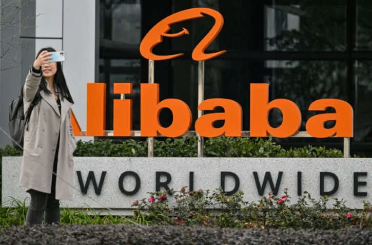 Une passante prend un selfie devant le logo d'Alibaba dans le quartier de Xuhui à Shanghai, le 22 février 2025
